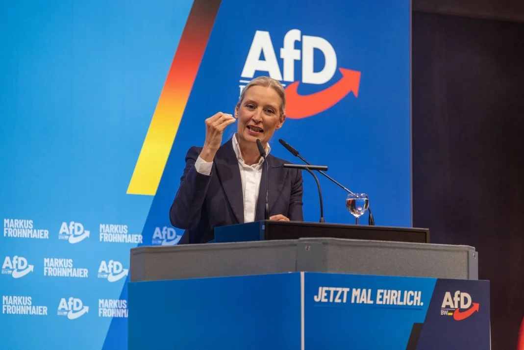 Photo by Alice Weidel on February 13, 2026. May be an image of one or more people, microphone and text that says 'AfD MARKUS FROHNMAIER 品 IS AfD MARKUS FROHNMAIER AfD AfD MARKUS FROHNMAIER AFD MARKUS FROHNMAIER SN BNT AfD MARKUS FROHNMI JETZTMALEHRLICH.AFD EW JETZT MAL EHRLICH. AfD'.